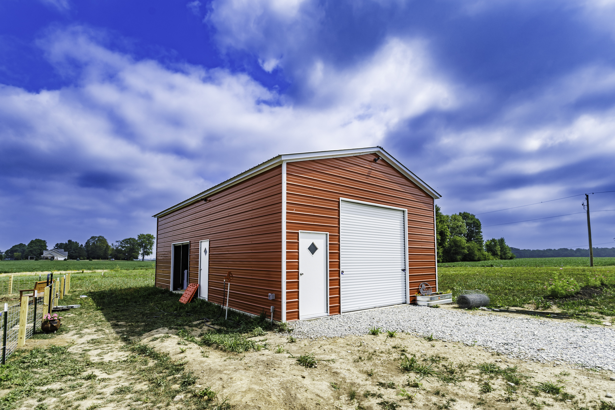 Custom steel garage with barn red siding and white trim on Indiana farmland