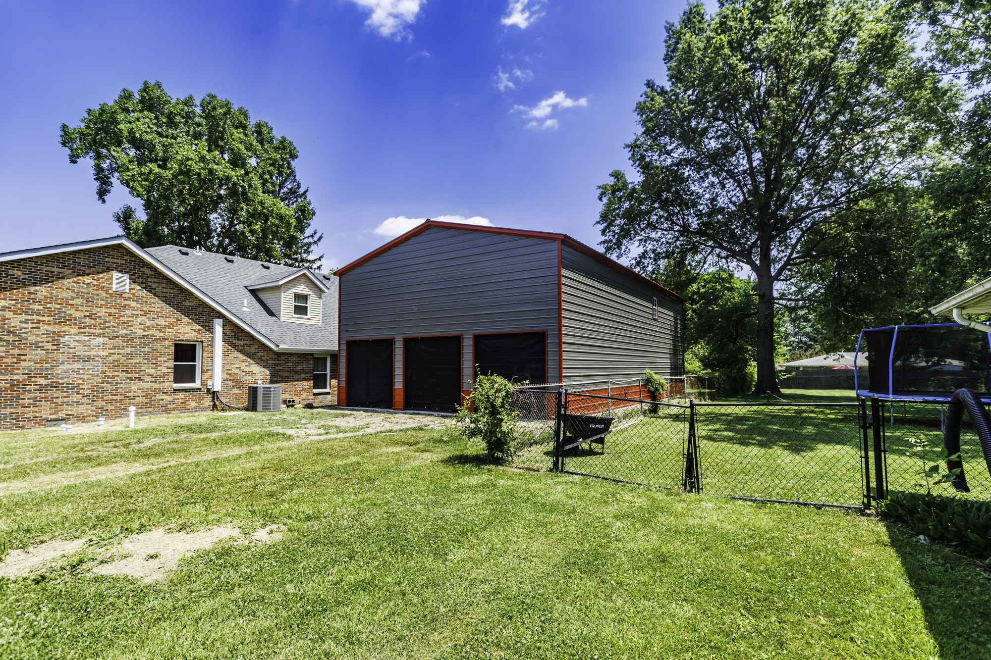 Large white steel garage with two roll-up doors and black wainscoting