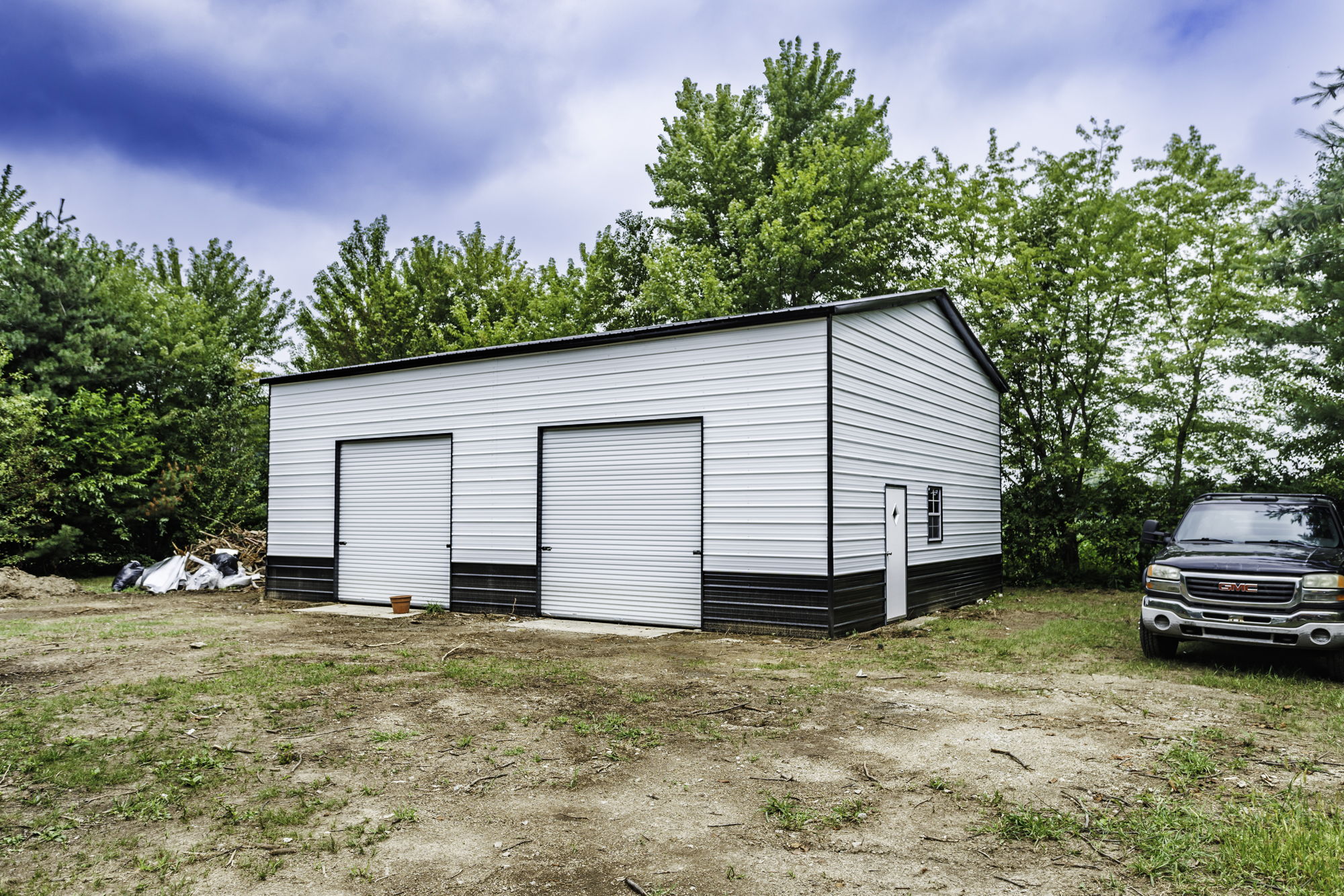 White and blue steel building with lean-to carport attachment on green lawn